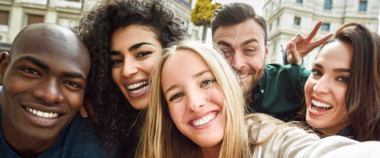 Nell'immagine cinque ragazzi sorridenti che si scattano un selfie